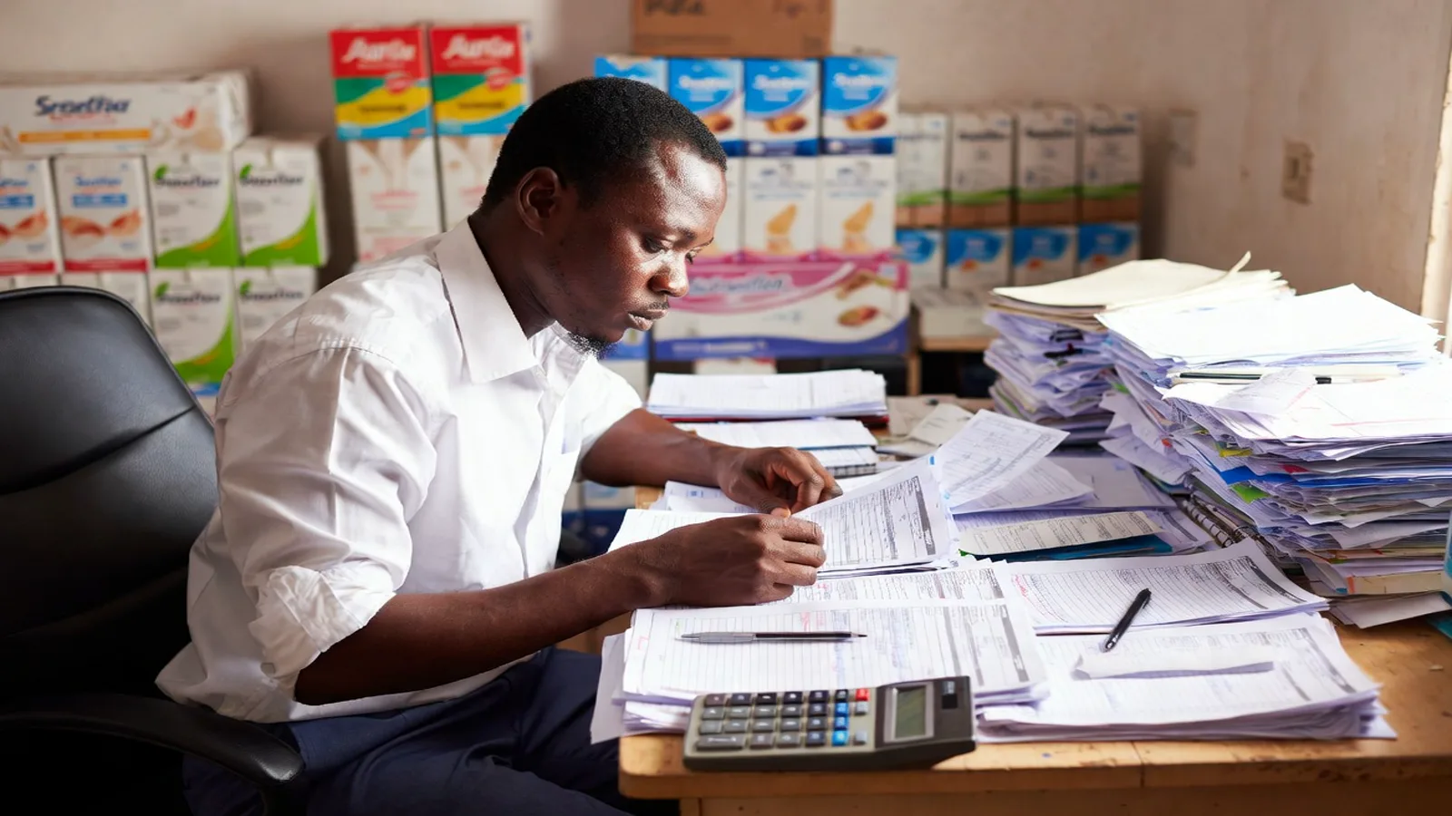 Nigerian FMCG finance manager reviewing unpaid invoices and retail payment delays